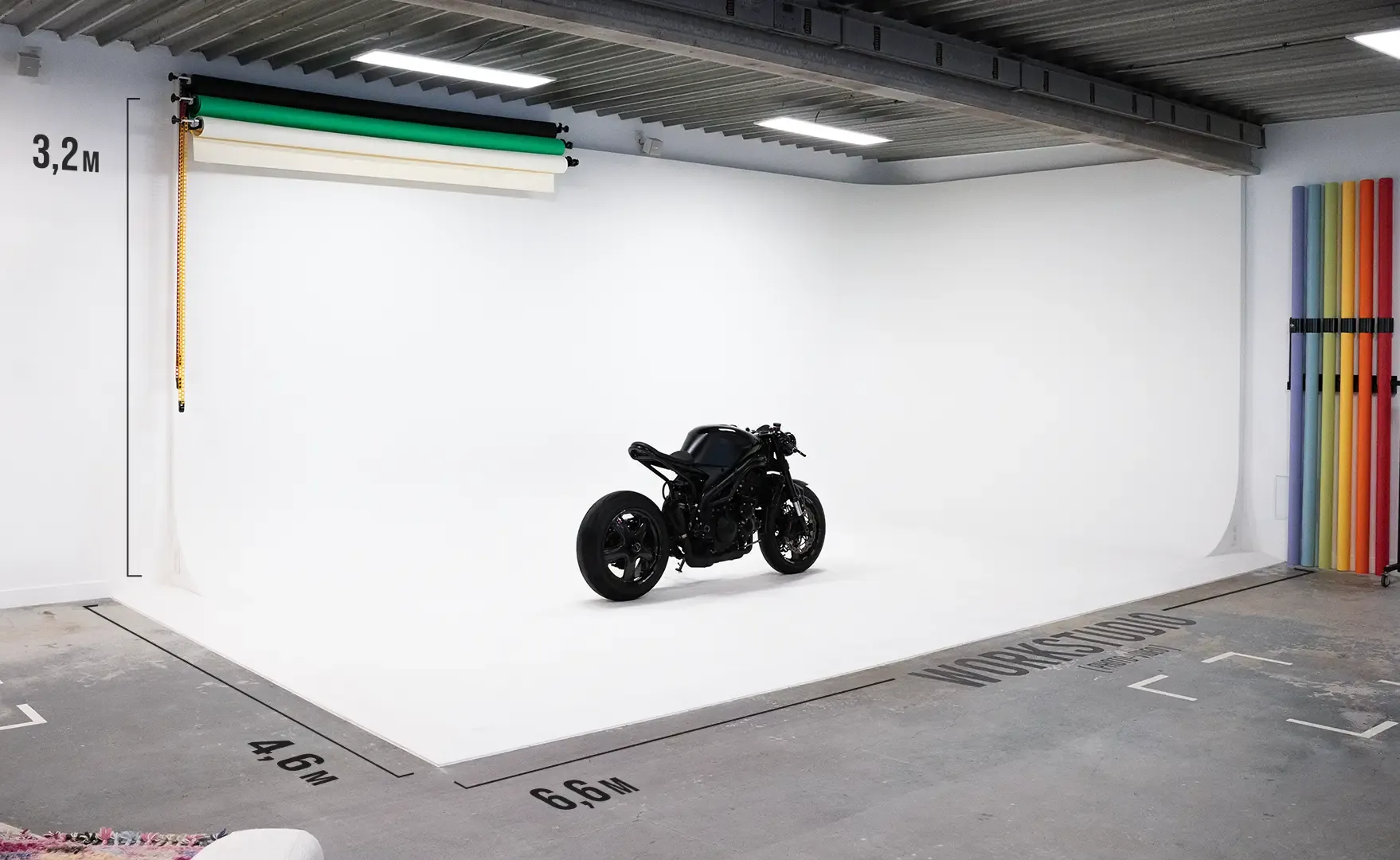 Le cyclorama blanc du Workbrand Studio, une moto noire au centre, cotes peintes au sol